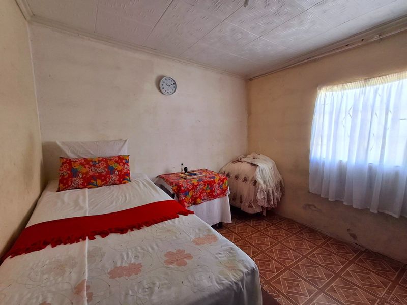 A bedroom featuring tiled flooring and textured ceiling tiles, requiring cosmetic updates to the wall finishes to improve the overall aesthetic.