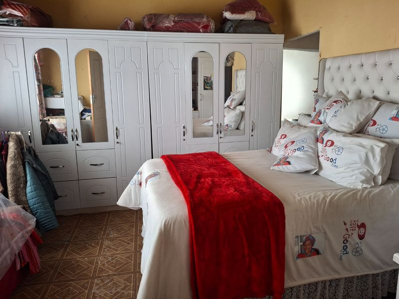 A bedroom featuring a large white built-in wardrobe with mirrored panels and tiled flooring.