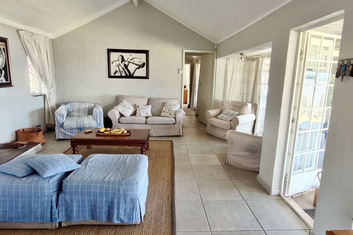 Spacious living room featuring a vaulted ceiling, tiled flooring, and a freestanding fireplace, with direct access to the outdoor area through french doors.