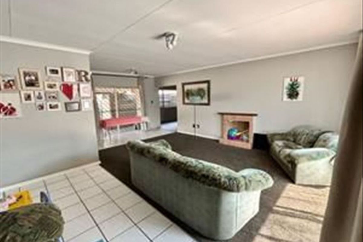 Spacious living room featuring a fireplace, tiled and carpeted flooring, and an open-plan layout leading to an adjacent area.