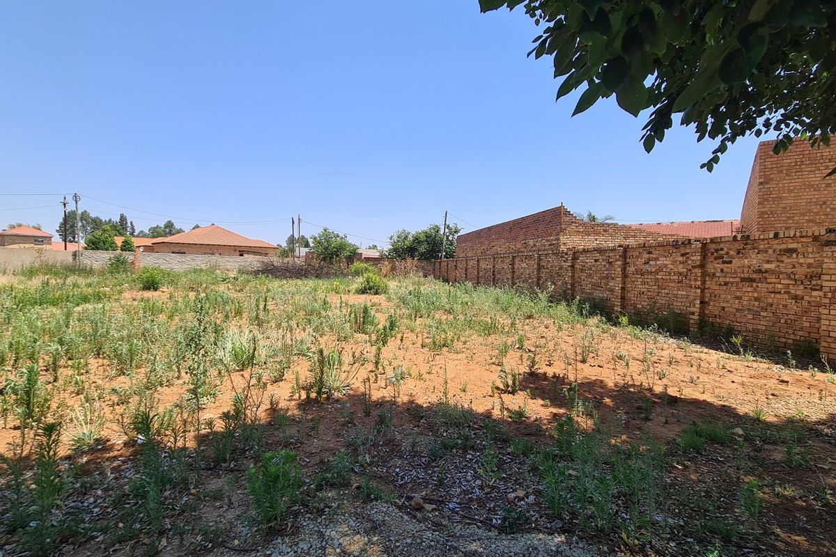 A vacant residential plot featuring established brick boundary walls and natural ground cover, ready for development.