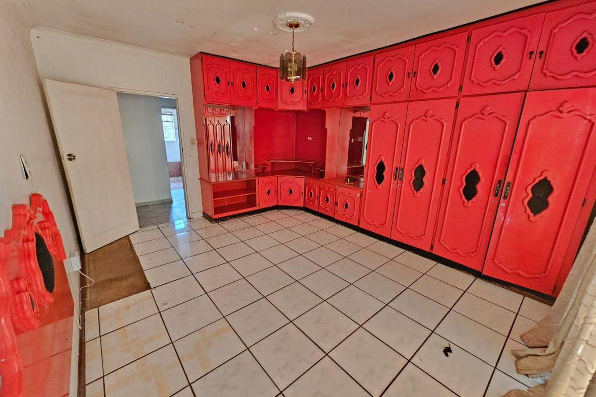 Spacious bedroom featuring extensive built-in cabinetry and ceramic tiled flooring, requiring cosmetic updates to modernize the interior finishes.