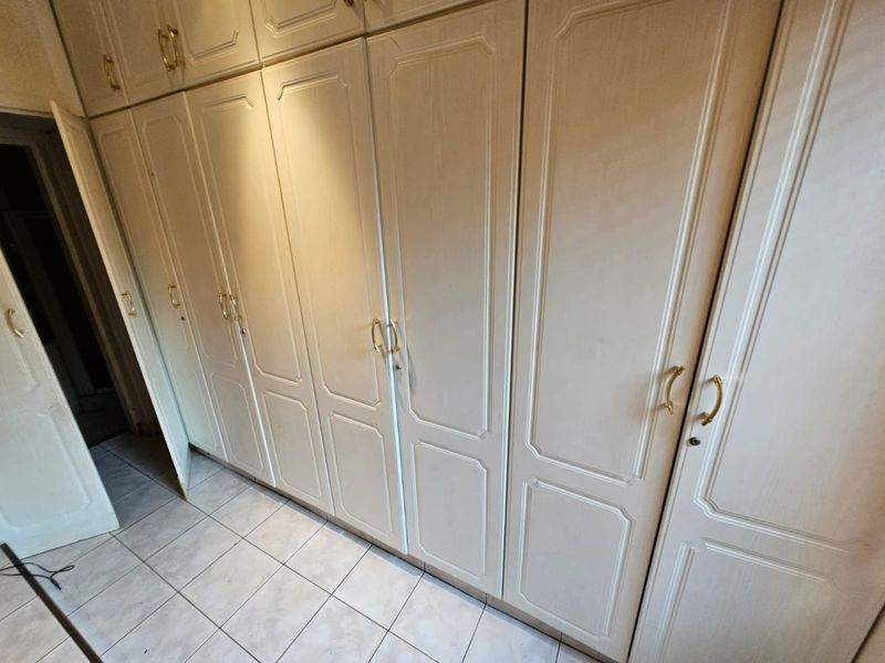 A bedroom featuring extensive built-in cabinetry with classic panel detailing and neutral tiled flooring.