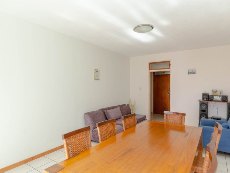 A functional living and dining area featuring tiled flooring and neutral walls, providing a versatile space for relaxation and meals.