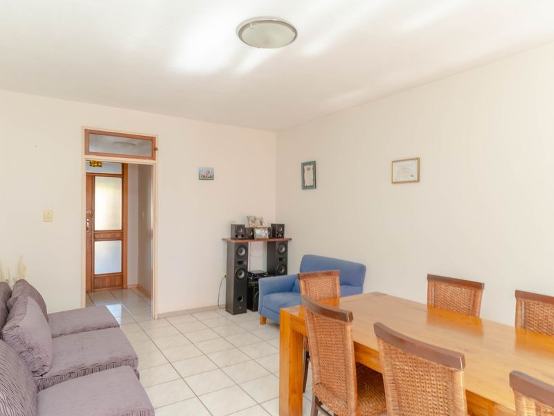 An open-plan living and dining area featuring neutral walls and tiled flooring, providing a functional space for daily living and entertaining.