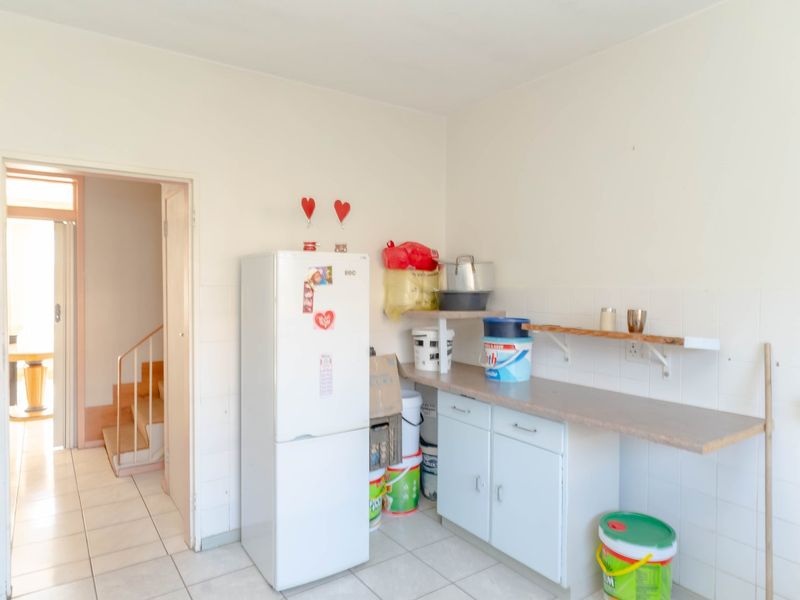 A functional scullery area featuring tiled flooring, built-in base cabinetry, and wall-mounted shelving, providing practical utility space for the home.