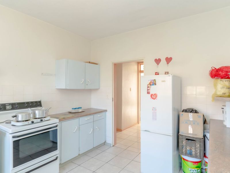 A functional kitchen featuring dated cabinetry, tiled backsplash, and tiled flooring, offering potential for modernization and renovation.