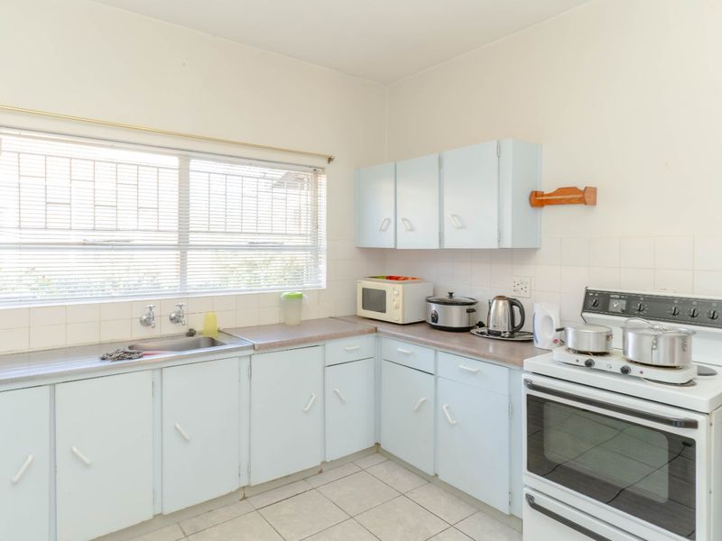 A functional kitchen featuring light blue cabinetry, laminate countertops, a tiled backsplash, and a freestanding stove, offering potential for modern updates.