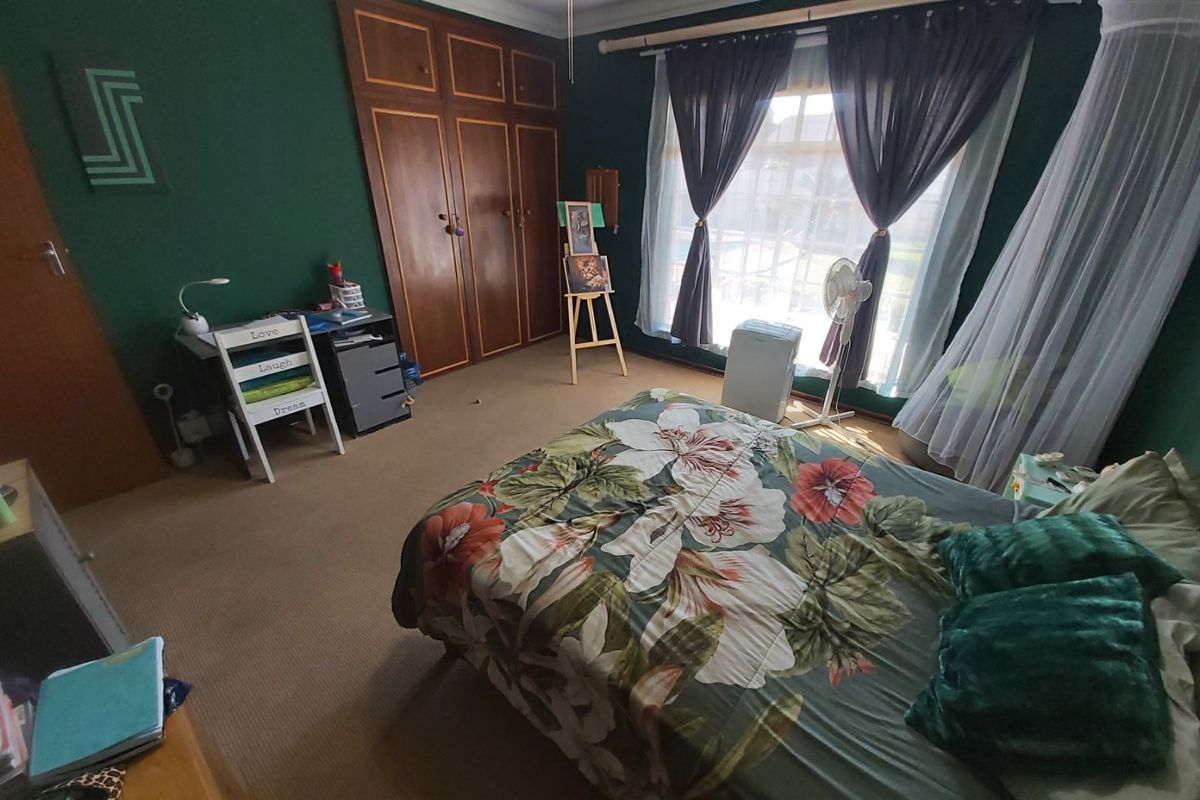 A bedroom featuring dark green walls, carpeted flooring, and built-in wooden cupboards, providing ample storage space.