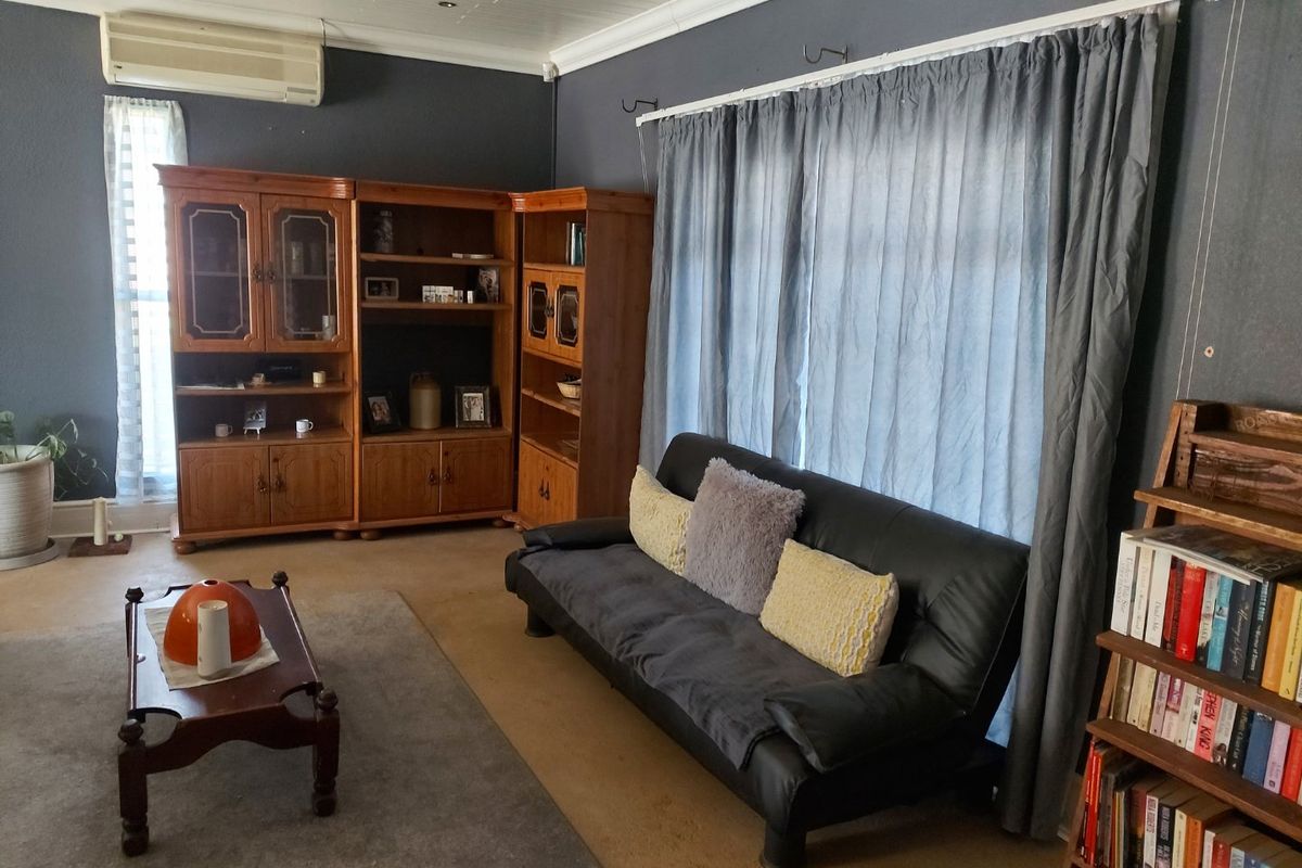 A living room featuring dark grey walls, recessed downlighting, and a wall-mounted split-system air conditioning unit.