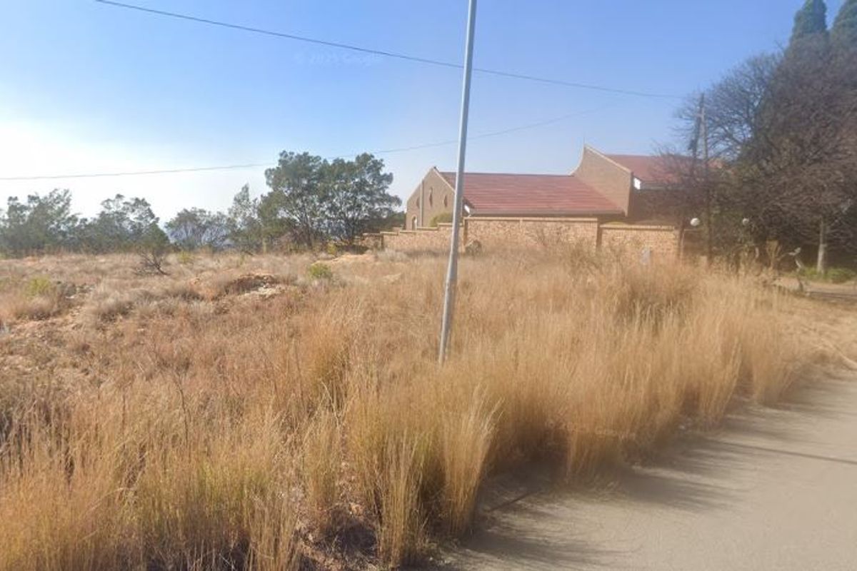 A view of a vacant residential plot featuring natural dry grass vegetation and a street-side utility pole.