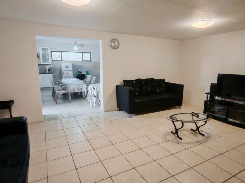 Open plan living area featuring tiled flooring and neutral walls, seamlessly connecting to an adjacent dining and kitchen space.