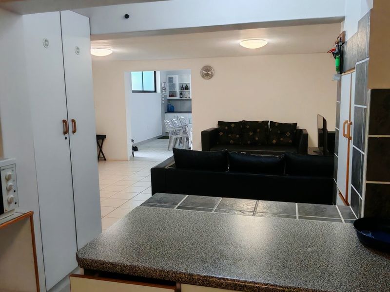 Open plan living area featuring tiled flooring, built-in cabinetry, and a functional kitchen counter space connecting to the lounge.