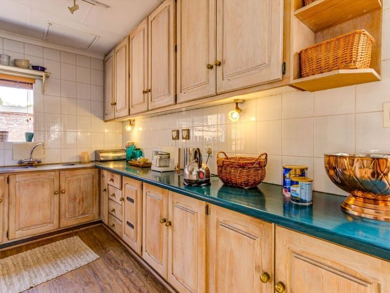 A functional kitchen featuring traditional wooden cabinetry, a tiled backsplash, and a laminate countertop with integrated sink and under-cabinet lighting.