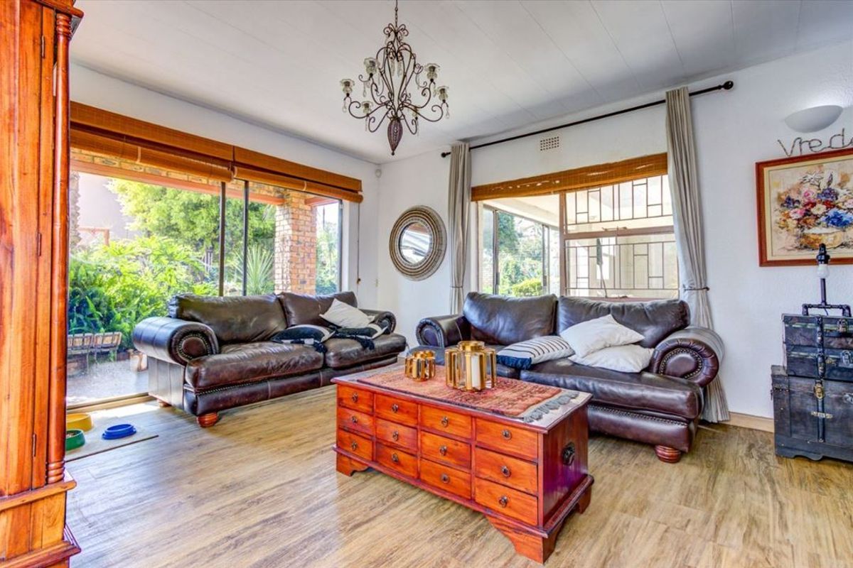 A bright living room featuring laminate flooring, a decorative chandelier, and large sliding glass doors providing access to the outdoor area.