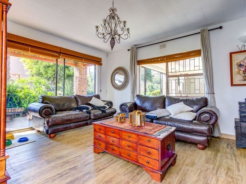 A bright living room featuring laminate flooring, a decorative chandelier, and large sliding glass doors providing access to the outdoor area.