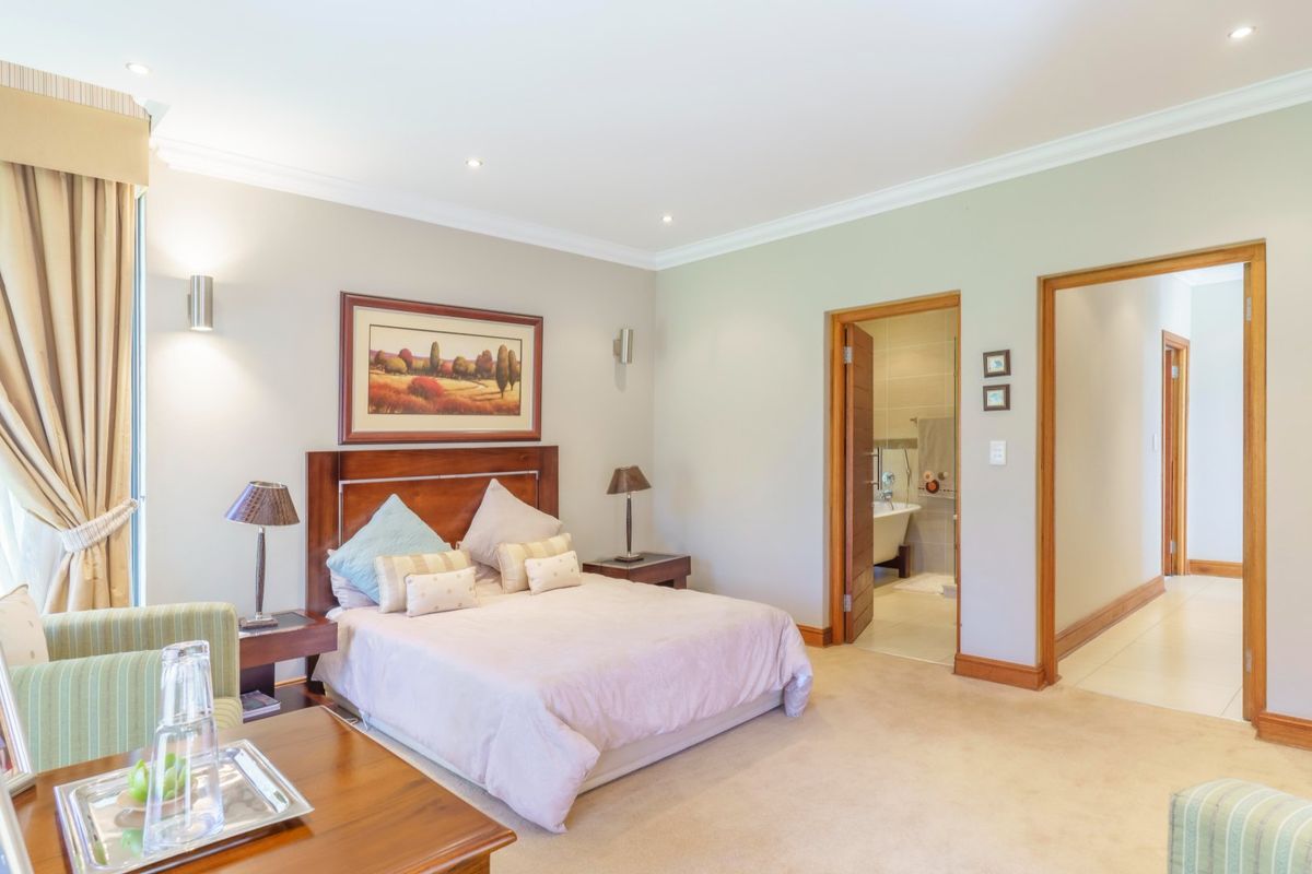 Spacious bedroom featuring neutral wall tones, plush carpeting, recessed downlighting, and direct access to an en-suite bathroom.