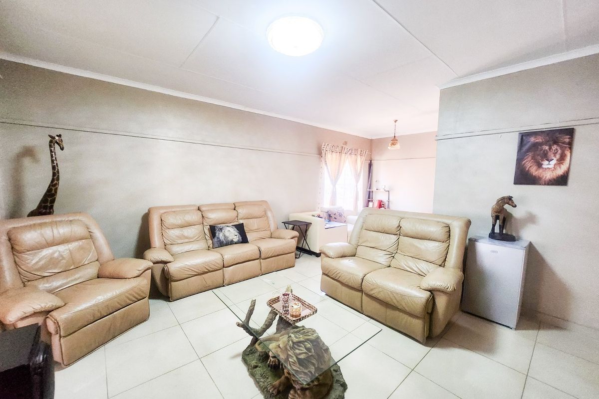 A spacious living room featuring neutral wall tones and large format floor tiles, providing a functional and comfortable area for relaxation.