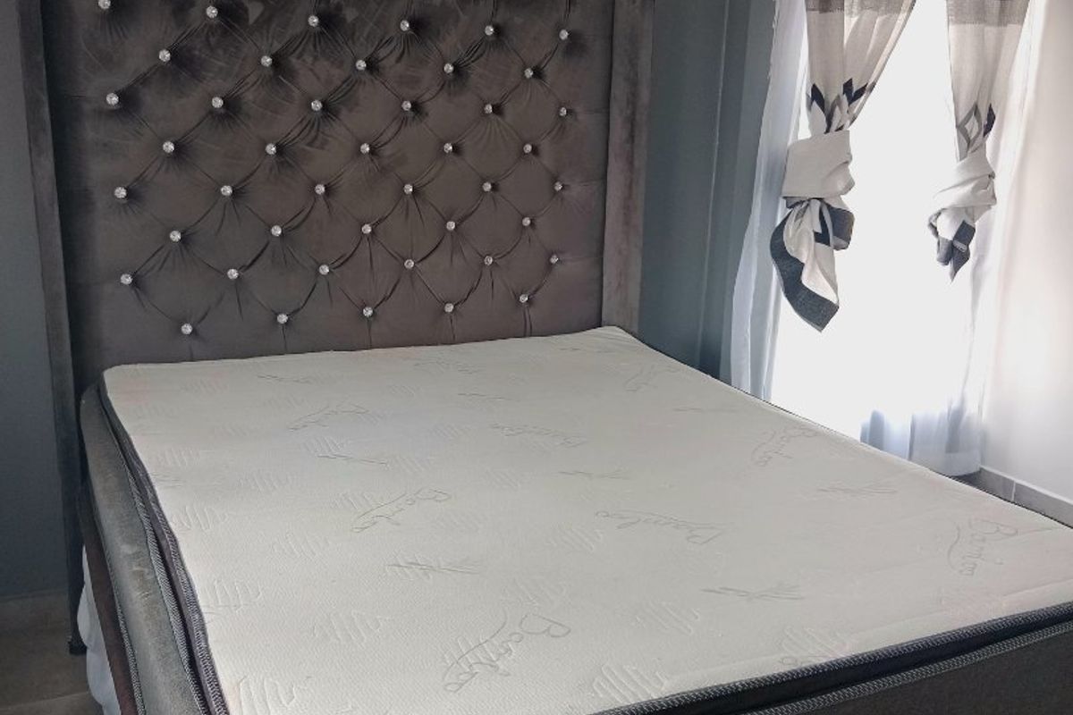 A well-lit bedroom featuring neutral grey walls and tiled flooring, providing a comfortable and functional sleeping space.