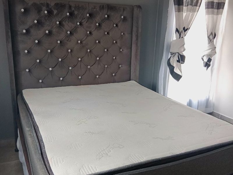 A well-lit bedroom featuring neutral grey walls and tiled flooring, providing a comfortable and functional sleeping space.