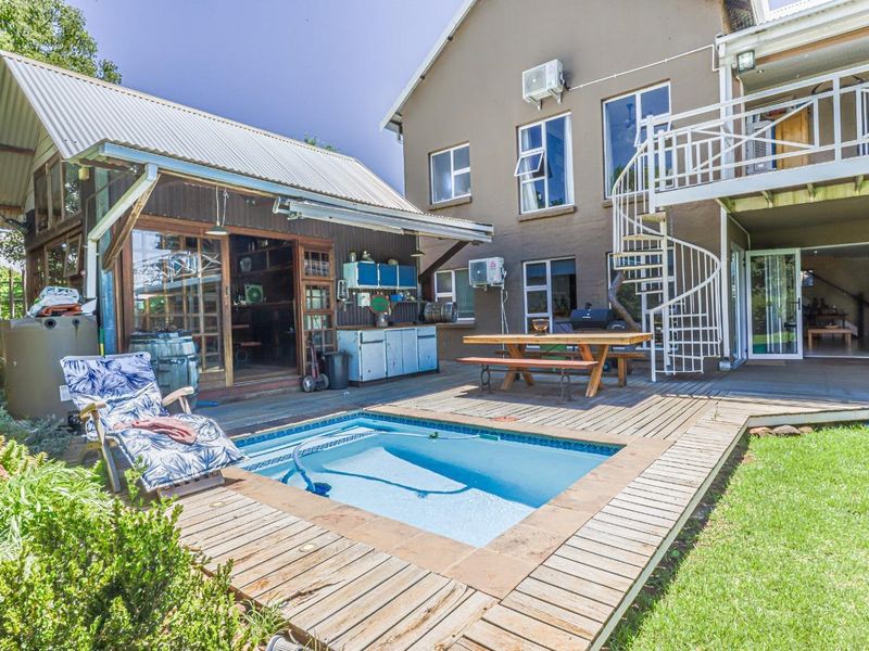 Outdoor entertainment area featuring a swimming pool, timber decking, spiral staircase, and direct access to the main house and secondary structure.