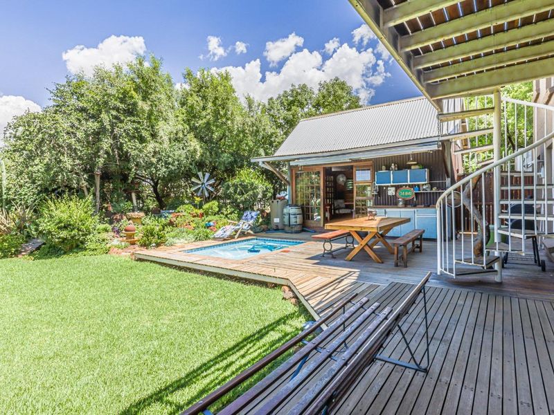 Outdoor entertainment area featuring timber decking, a plunge pool, and a spiral staircase leading to an upper level, set within a landscaped garden.