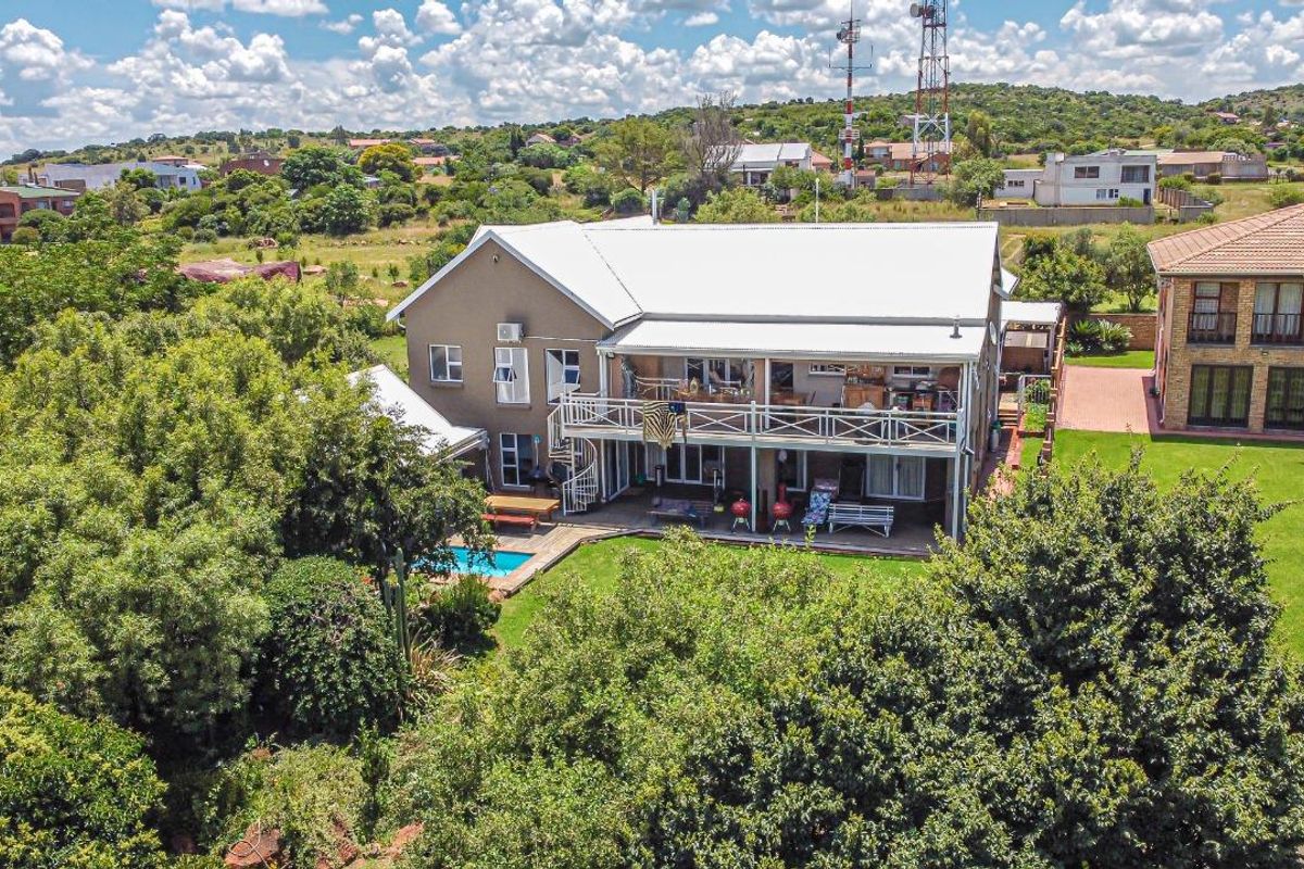 Aerial view of a two-story residential property featuring a metal roof, a spacious balcony with a spiral staircase, and a private swimming pool.