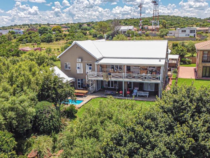 Aerial view of a two-story residential property featuring a metal roof, a spacious balcony with a spiral staircase, and a private swimming pool.