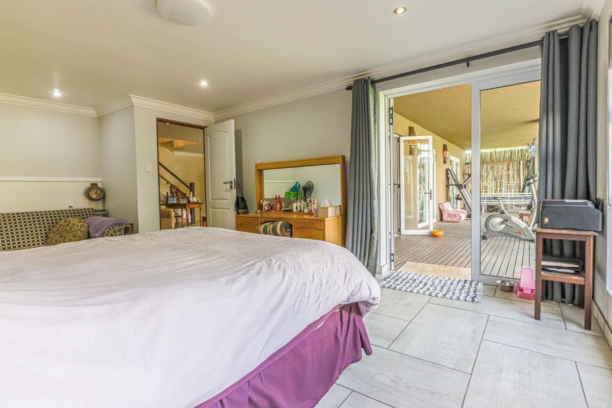 Spacious bedroom featuring tiled flooring, recessed lighting, and large sliding glass doors providing direct access to an outdoor patio area.