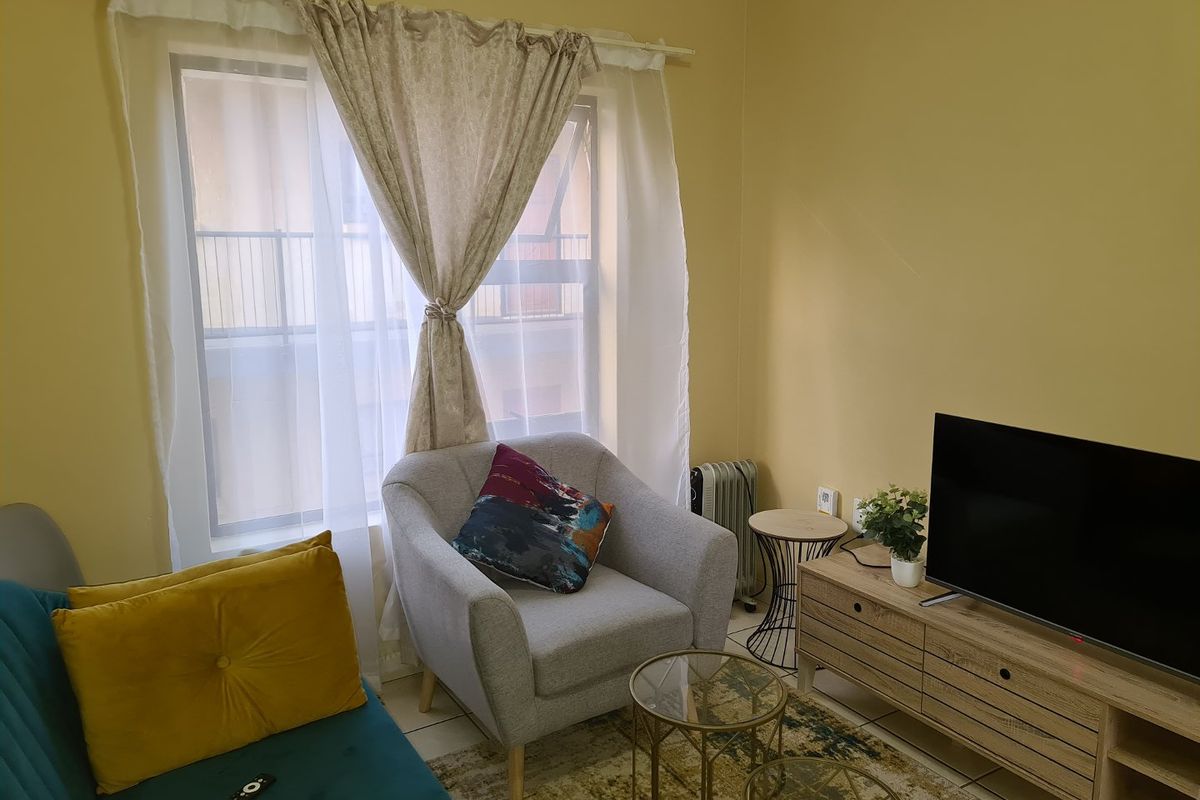 A cozy living room area featuring tiled flooring and a large window that allows for natural light.