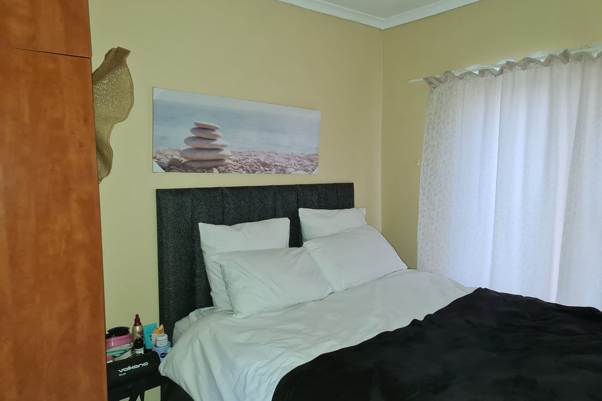 A bedroom featuring built-in wooden cabinetry and a window with curtains, providing a functional and comfortable sleeping space.