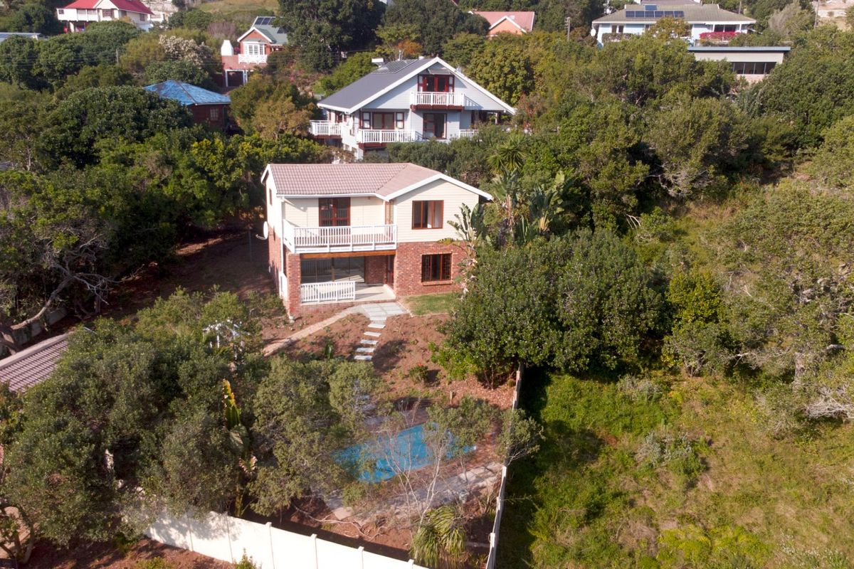 Aerial view of a two-story residential house featuring a swimming pool, balcony, and established garden surroundings in a leafy neighborhood.