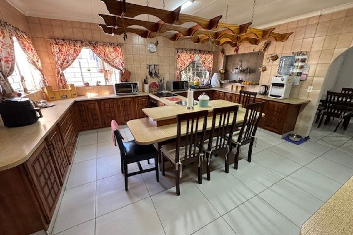 Spacious kitchen featuring extensive wooden cabinetry, laminate countertops, a central breakfast bar, and a unique suspended wooden ceiling feature.