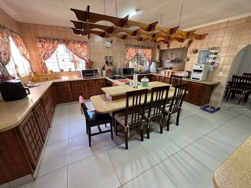 Spacious kitchen featuring extensive wooden cabinetry, laminate countertops, a central breakfast bar, and a unique suspended wooden ceiling feature.