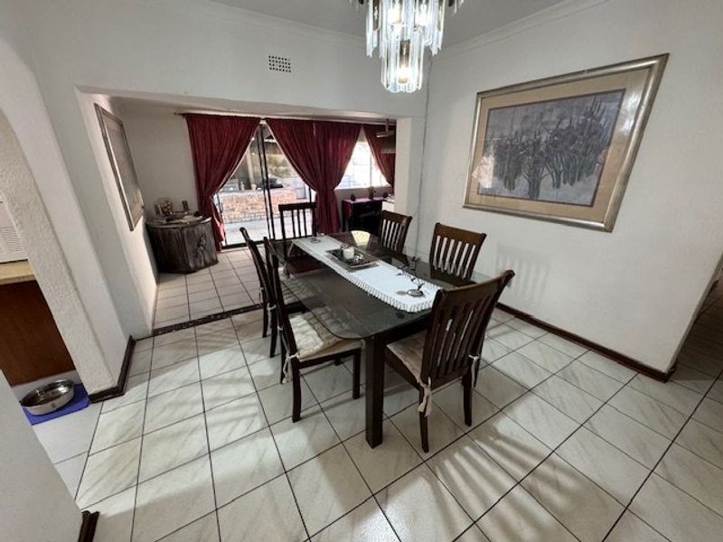 A dining room featuring tiled flooring, a coved ceiling, and a sliding glass door providing access to the outdoor area.