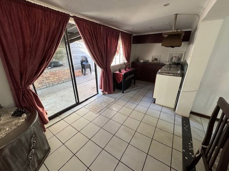 A functional kitchen area featuring tiled flooring, built-in cabinetry, and sliding glass doors providing direct access to the outdoor patio space.