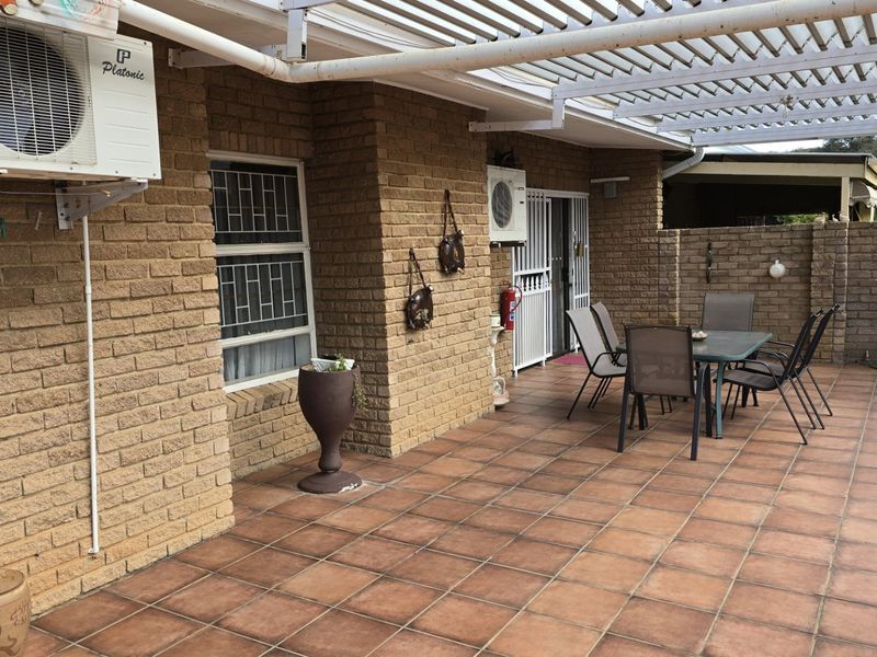 Covered outdoor patio featuring brick walls, tiled flooring, and a pergola structure, providing a functional space for outdoor living and entertainment.