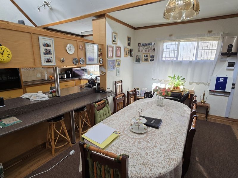 Open plan kitchen and dining area featuring a breakfast bar, laminate flooring, and integrated solar inverter system, offering a functional layout for daily living.
