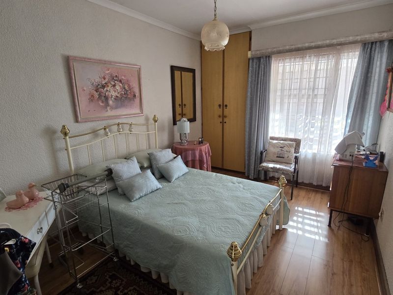 A bedroom featuring laminate flooring and a built-in wardrobe, offering a functional space with natural light from the window.
