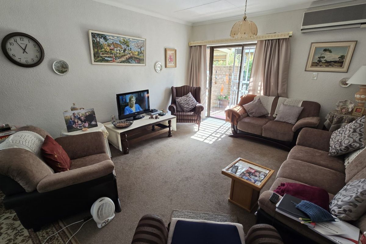 A comfortable living room featuring carpeted flooring, an air conditioning unit, and a sliding glass door providing access to the outdoor area.