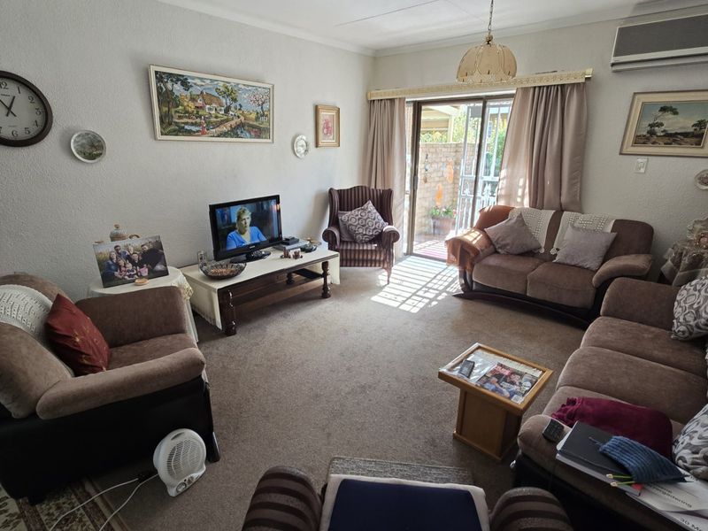 A comfortable living room featuring carpeted flooring, an air conditioning unit, and a sliding glass door providing access to the outdoor area.