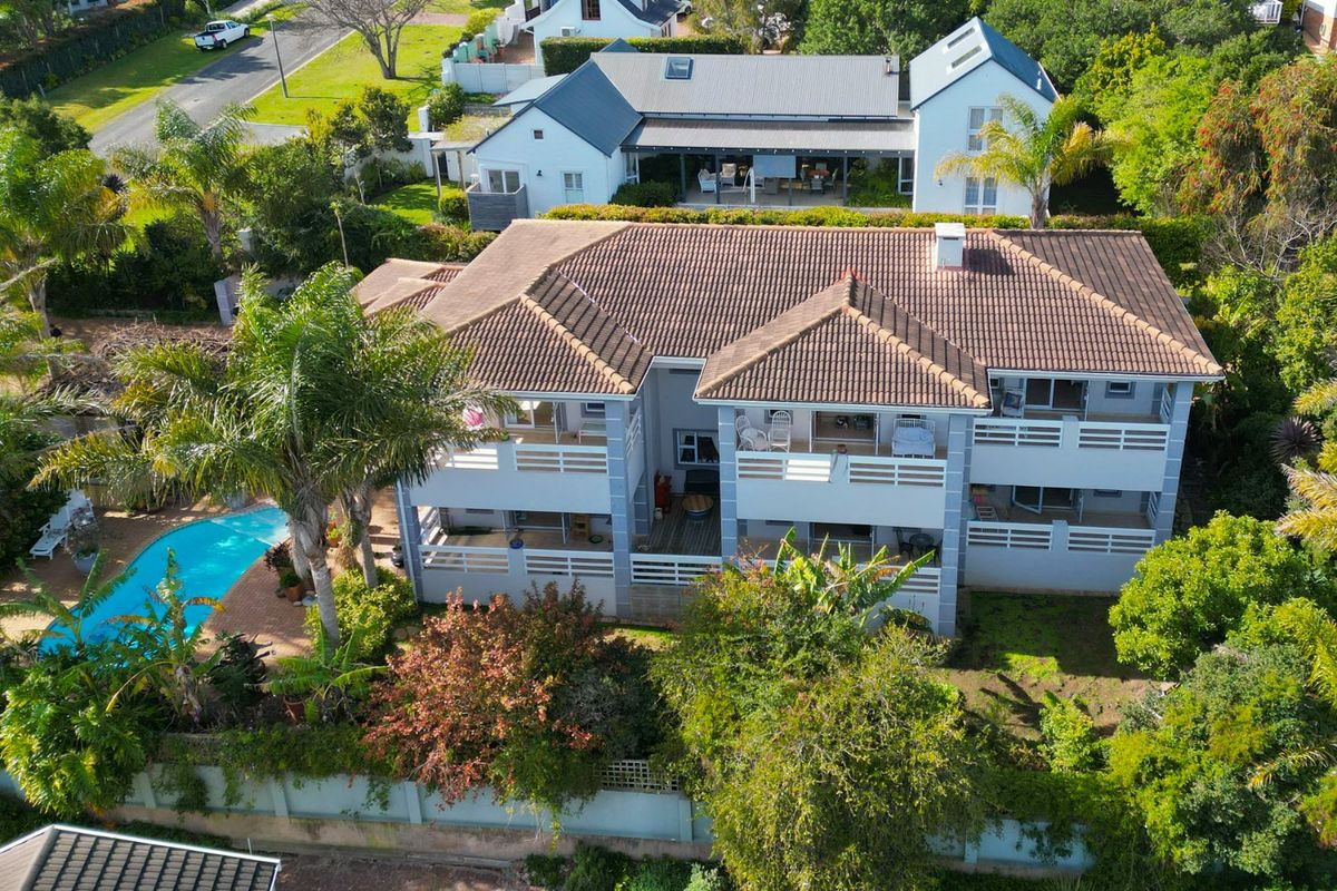 Aerial view of a two-story residential property featuring a tiled roof, multiple balconies, and a swimming pool set within a landscaped garden.