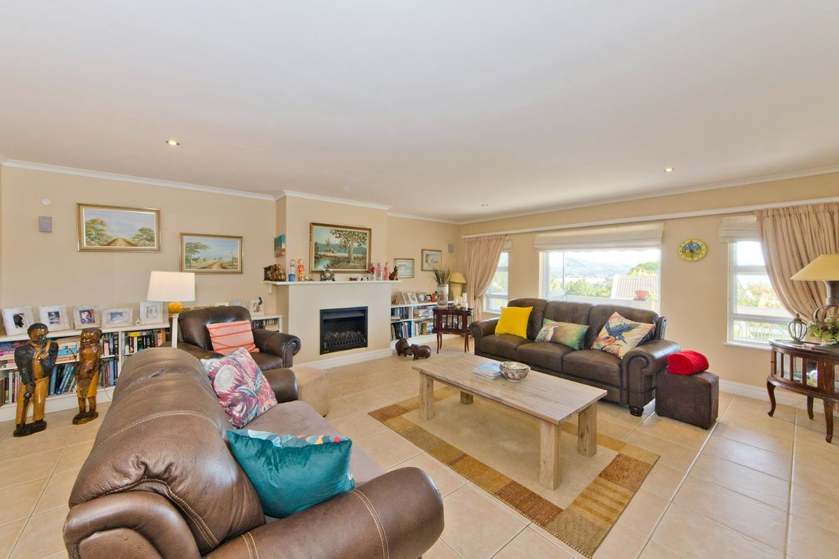 Spacious living room featuring a built-in fireplace, neutral tiled flooring, recessed lighting, and large windows providing natural light and views.