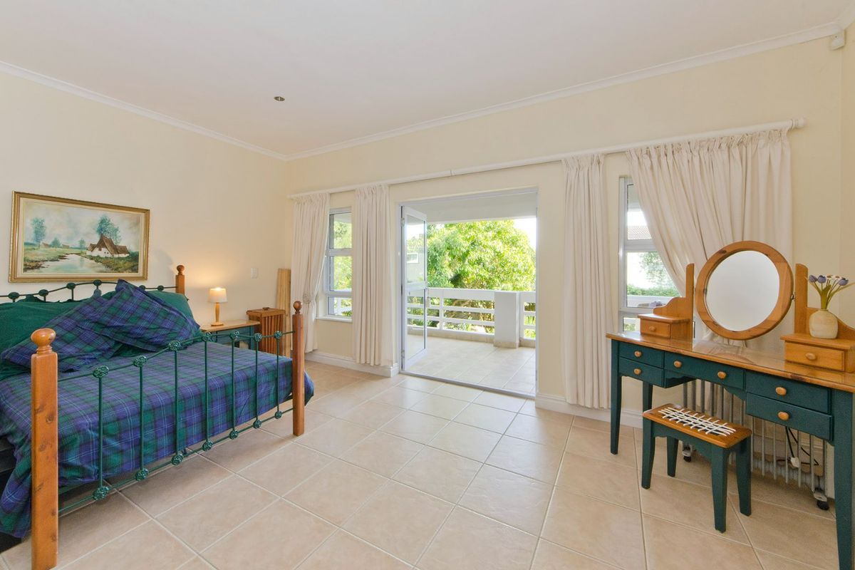 Spacious bedroom featuring neutral tiled flooring, recessed lighting, and direct access to a private balcony through sliding glass doors.