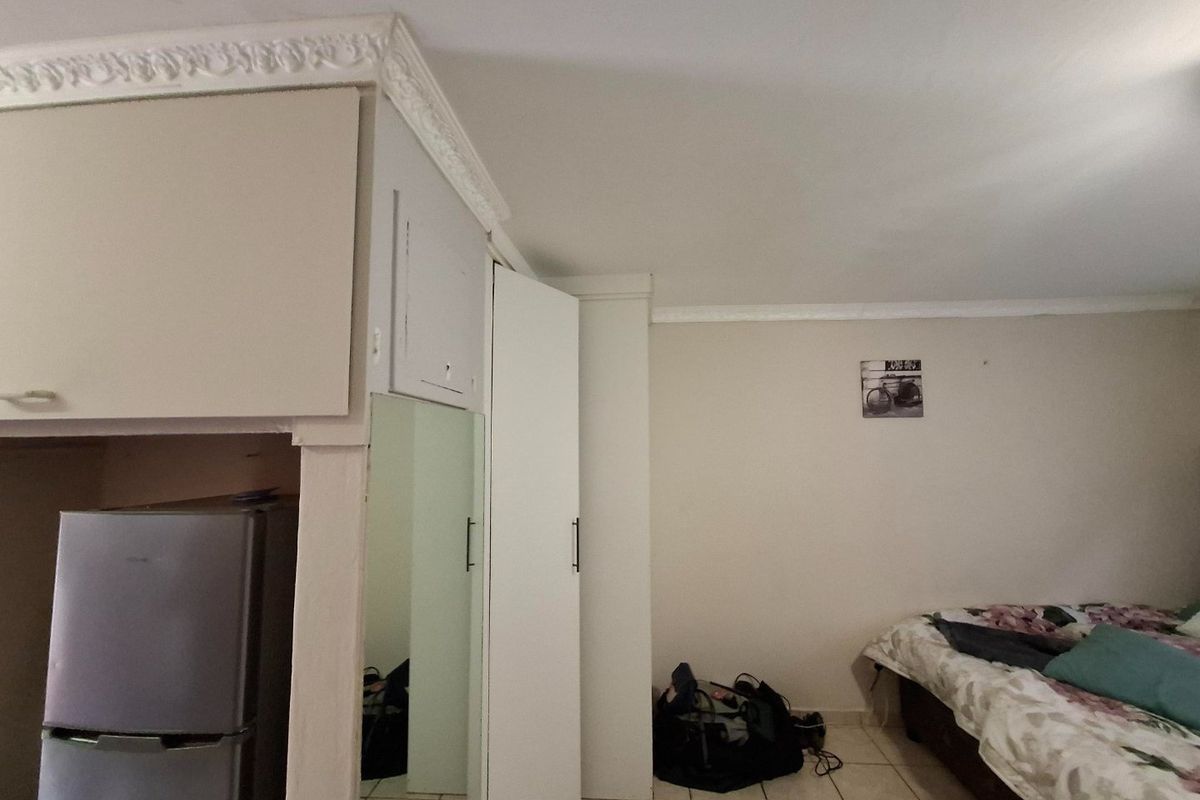 Bedroom featuring built-in cupboards with a mirrored door, decorative ceiling cornicing, and tiled flooring.