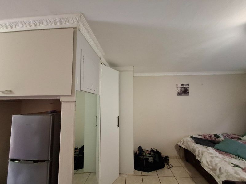 Bedroom featuring built-in cupboards with a mirrored door, decorative ceiling cornicing, and tiled flooring.