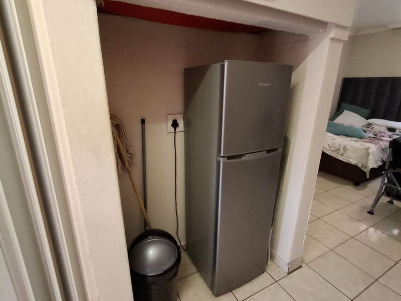 A utility alcove featuring tiled flooring and built-in overhead storage, currently utilized for appliance placement.