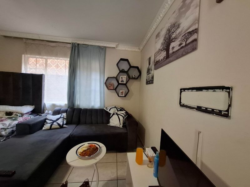 A living room area featuring tiled flooring and decorative ceiling cornicing, providing a functional space for relaxation.