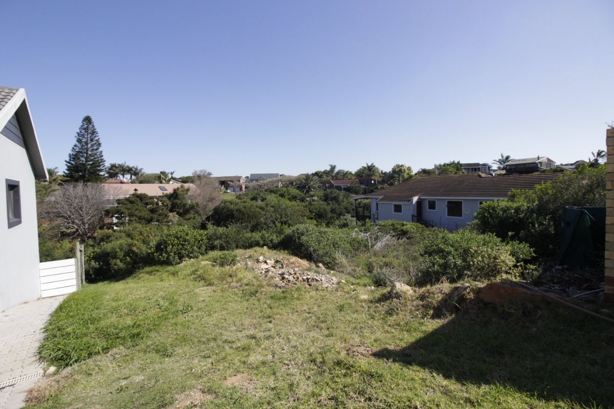 A view overlooking a sloped residential plot with established native vegetation and surrounding neighborhood properties.