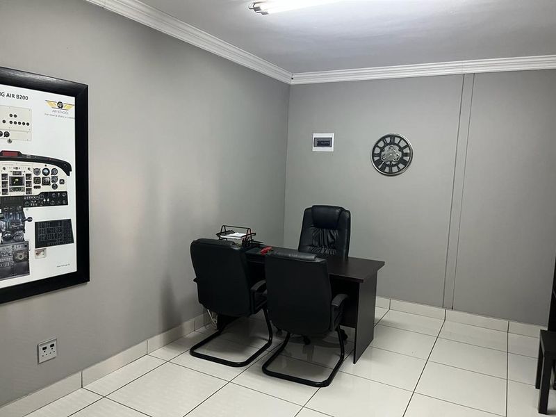 A functional commercial office space featuring neutral grey walls, white tiled flooring, and classic cove cornice detailing.